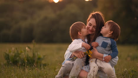 Mother-hugging-her-two-sons-in-the-sunset-in-the-field.-Loving-kids-happy-mom